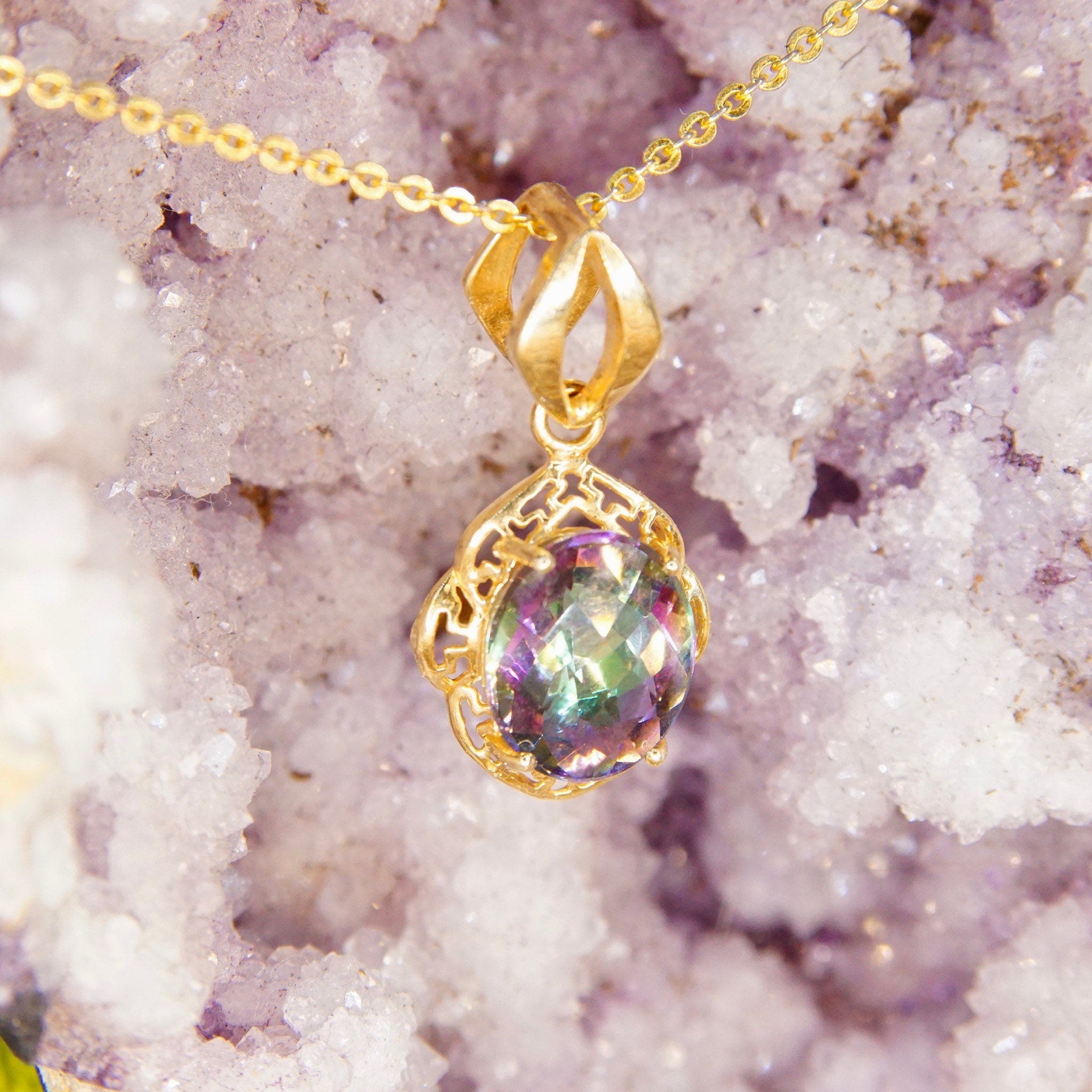 14K yellow gold vintage pendant necklace featuring an ornate setting with a faceted 26mm x 13mm mystic fire topaz gemstone displaying vibrant purple and green colors.