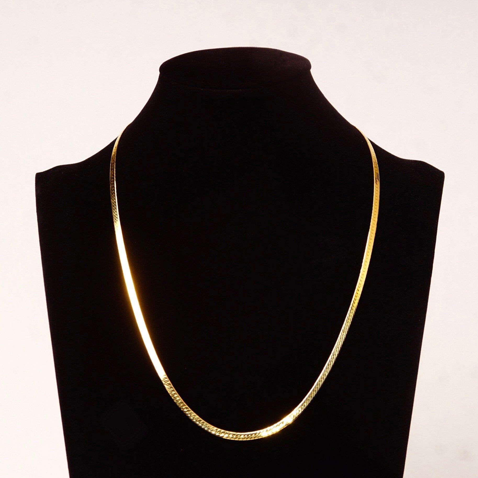Elegant 14K yellow gold Italian diamond-cut herringbone chain necklace with reversible design, measuring 3.5mm wide and 20 inches long, displayed on black velvet jewelry bust against white background.