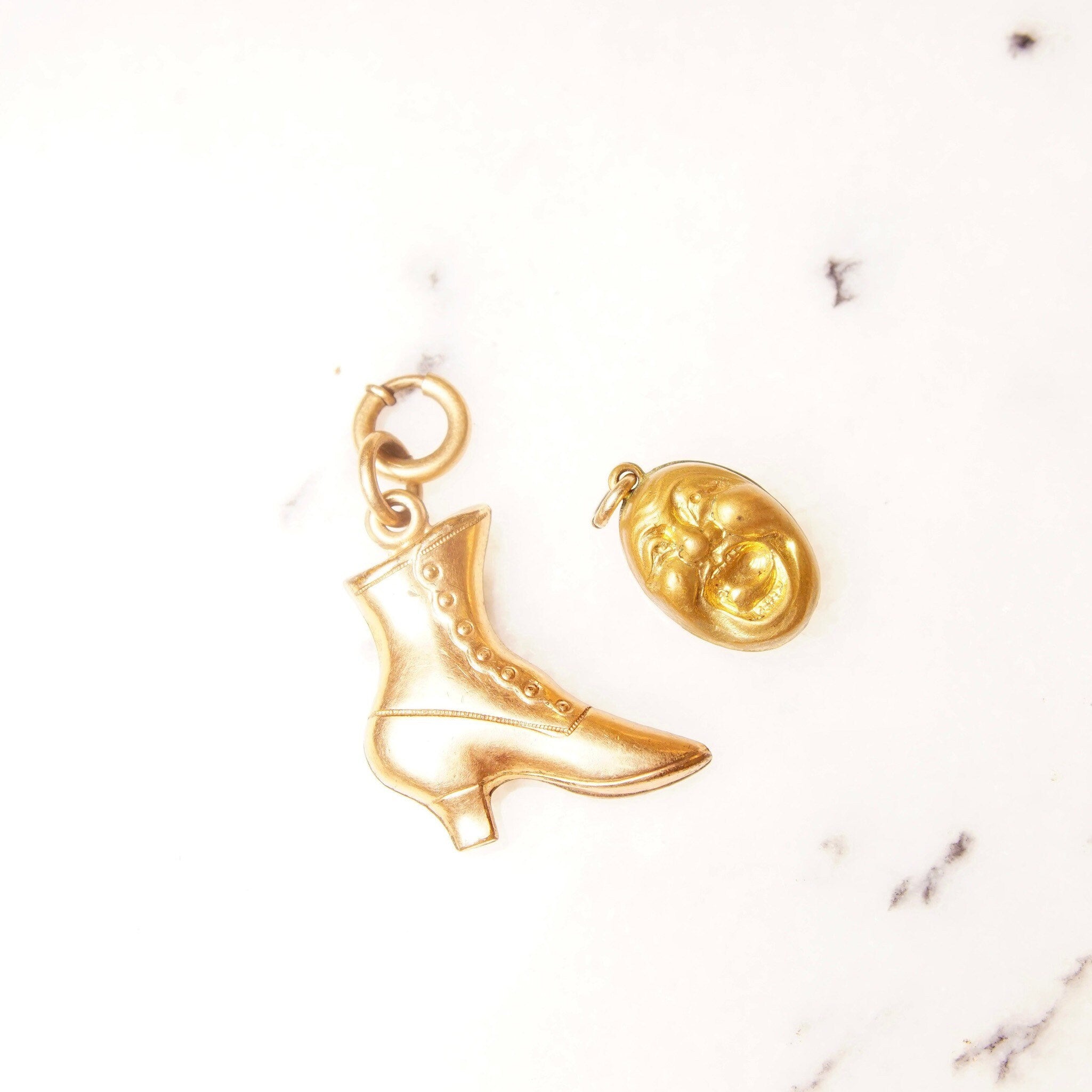 Vintage 10K gold plated charms featuring a rose gold Victorian boot charm and a yellow gold screaming head charm on a white marble background.