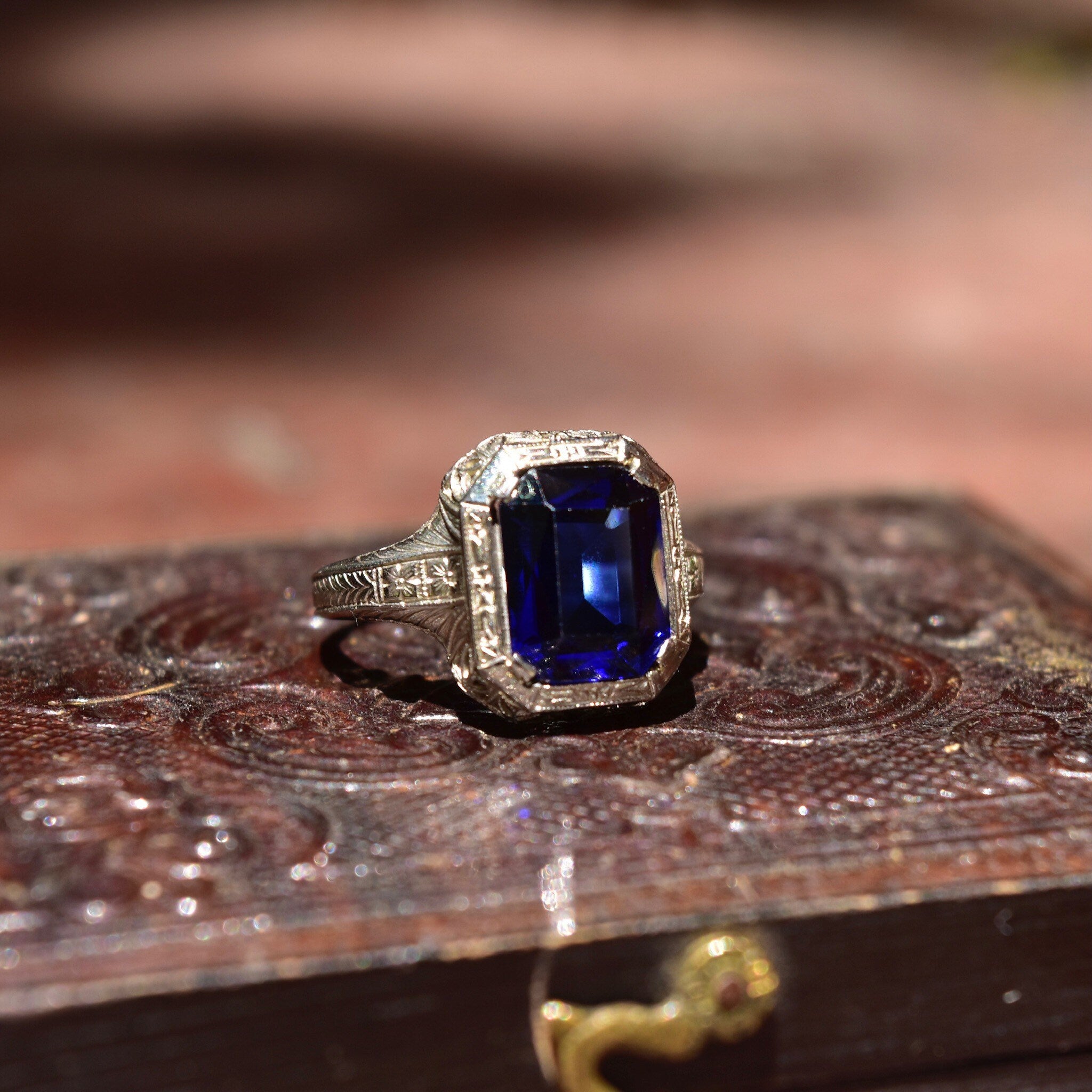 Antique Art Deco 14K white gold filigree ring with square-cut blue sapphire, intricate filigree inset, size 7 1/2 US, on textured wooden surface