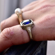 Antique Art Deco 14K white gold filigree ring with square-cut blue sapphire, worn on finger, showcasing intricate filigree inset and design, ring size 7 1/2 US.