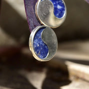 Vintage modernist sterling silver lapis lazuli yin-yang stud earrings with chunky solid silver studs and natural blue lapis lazuli gemstones, shown in close-up detail against a blurred neutral background.