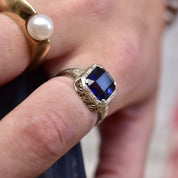 Antique Art Deco 14K white gold filigree ring featuring a square-cut blue sapphire gemstone, worn on a finger displaying intricate metal filigree details, ring size 7 1/2 US.