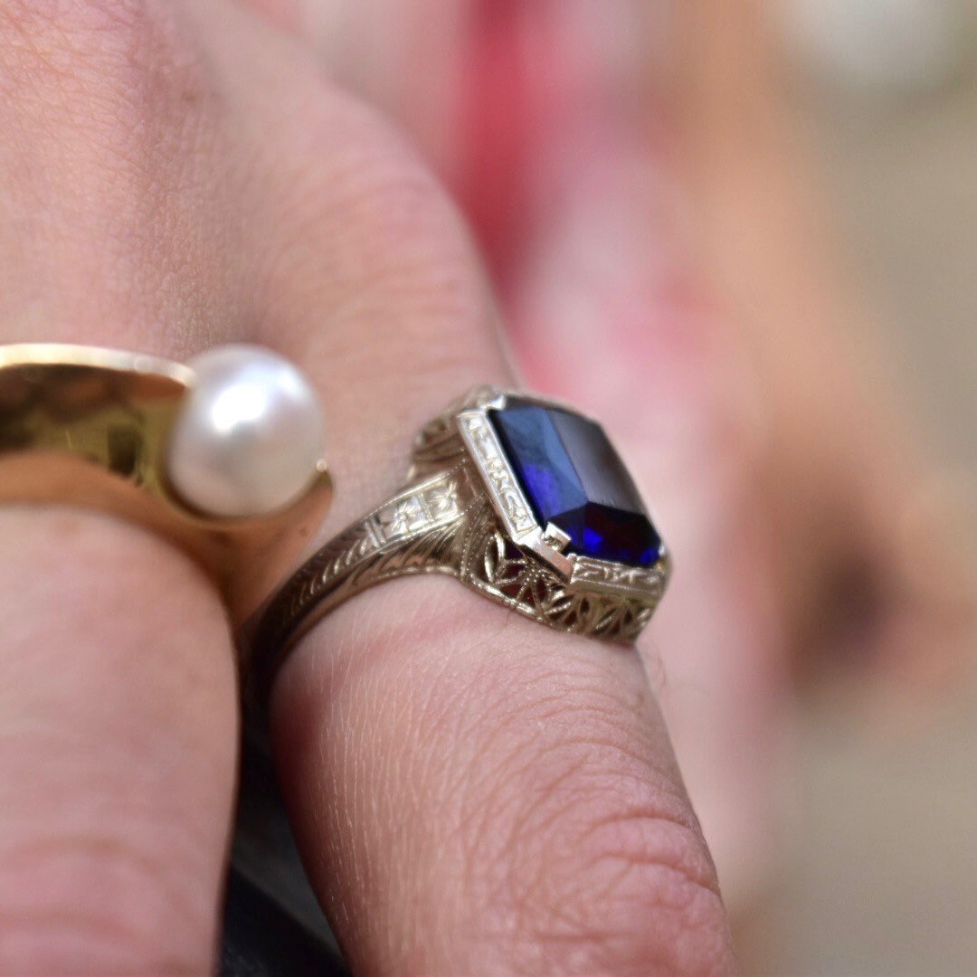 Antique Art Deco 14K white gold filigree ring with a square-cut blue sapphire stone, set on a hand displaying intricate filigree details, ring size 7 1/2 US.