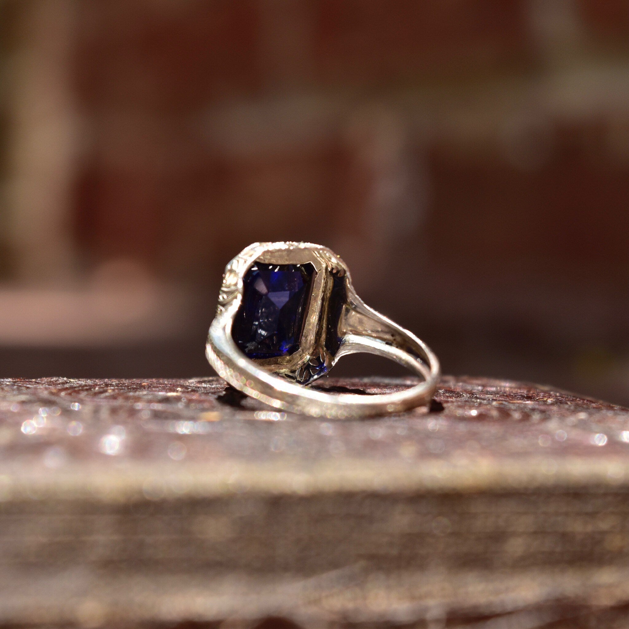 Antique Art Deco 14K white gold filigree ring with square-cut blue sapphire stone, intricate filigree inset, size 7 1/2 US, on rustic wooden surface