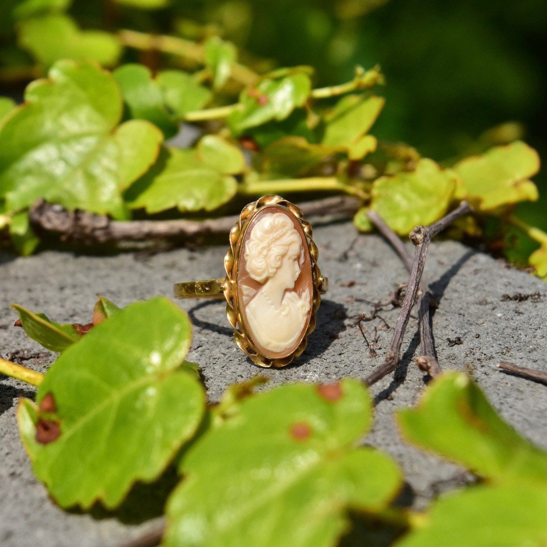 Vintage 10K gold cameo ring with classic relief shell carving, elongated oval shape, yellow gold ribbon setting, size 10 US displayed on natural background.
