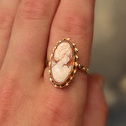Vintage 10K gold cameo ring with classic relief shell carving, size 10 US, showcased on a finger with an elongated oval shape and yellow gold ribbon setting.