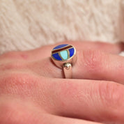 Vintage sterling silver ring with multi-stone inlay featuring lapis lazuli, turquoise, and carnelian, worn on a finger. Colorful scarab beetle design allows the top to flip. Size 8 US.