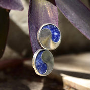 Vintage modernist sterling silver lapis lazuli yin-yang stud earrings with chunky solid silver and natural deep blue lapis lazuli gemstones, shown on a wooden surface.