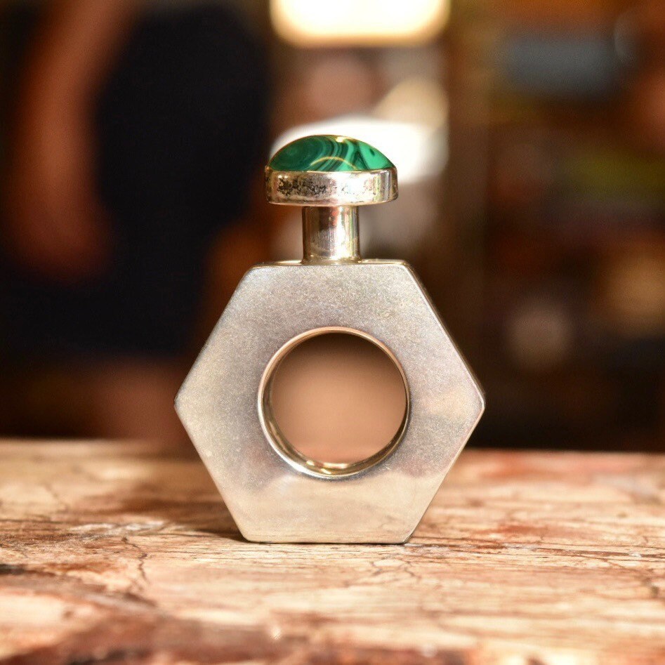 Alt text: Vintage TAXCO modernist sterling silver mini hexagonal perfume bottle with malachite top, 2 inches tall, sitting on wooden surface
