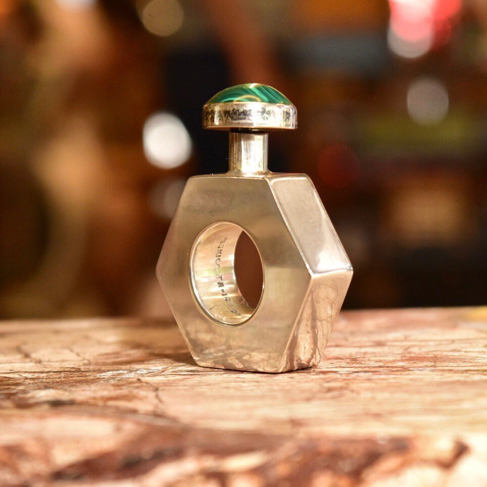 Vintage TAXCO modernist sterling silver perfume bottle with malachite stone top, mini hexagonal shape, stamped TA-187 Mexico, measuring 2 inches tall, on rustic wooden surface.