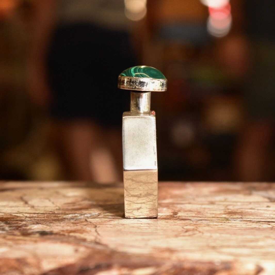 Vintage Taxco sterling silver hexagonal perfume bottle with malachite top, 2 inches tall, on a rustic wooden surface