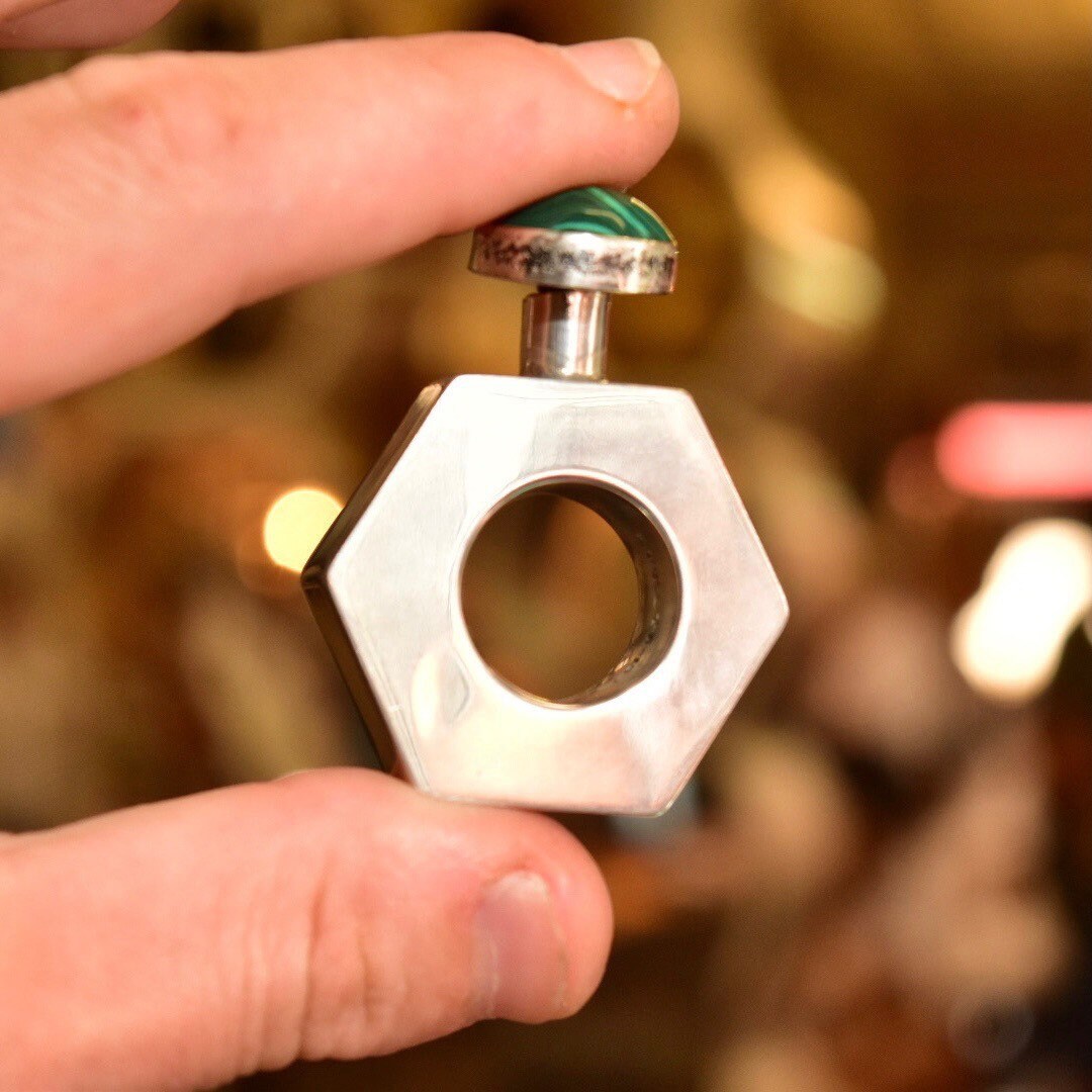Vintage TAXCO Mexico modernist sterling silver hexagonal mini perfume bottle with malachite cabochon top, held in hand to show scale and detail, 2 inches tall.