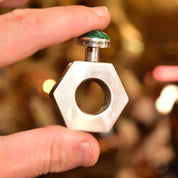 Vintage TAXCO Mexico modernist sterling silver hexagonal mini perfume bottle with malachite cabochon top, held in hand to show scale and detail, 2 inches tall.
