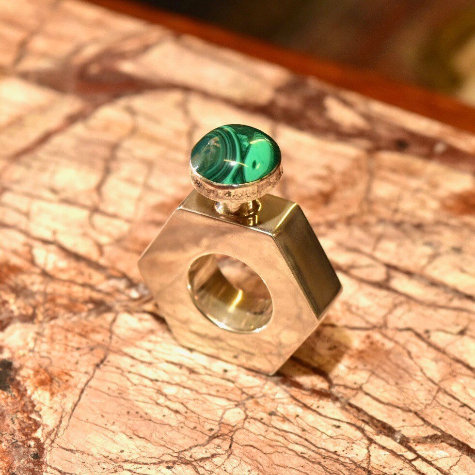 Sterling silver hexagonal perfume bottle with malachite green stone top, modernist vintage design from Taxco, Mexico, measuring 2 inches tall, on textured marble surface