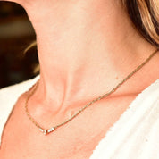 14K yellow gold diamond bar necklace with shared prong setting on a delicate 2mm Singapore chain, resting elegantly on a woman's neck.