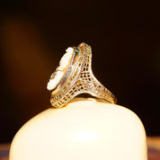 Antique 14K white gold filigree ring with carved shell cameo of a woman's profile wearing a diamond necklace, with additional diamond accents on the ring's ornate vintage setting, size 6 1/4 US by ESEMCO.
