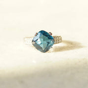 Vintage 14K white gold blue topaz solitaire ring with cushion cut gemstone, accent diamonds, and cathedral setting, size 7.5 US.