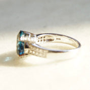Vintage 14K white gold blue topaz and diamond ring featuring a cushion cut blue topaz solitaire in a cathedral setting accented by small diamonds, cocktail ring style, size 7.5 US.