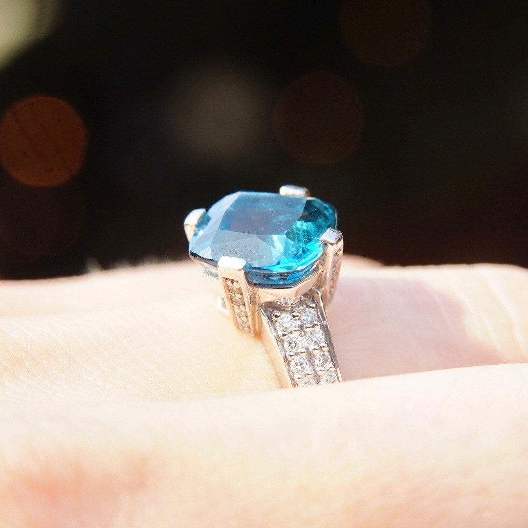 Vintage 14K white gold blue topaz solitaire ring featuring a cushion cut gemstone accented by diamonds in a cathedral setting, cocktail ring, size 7.5 US.