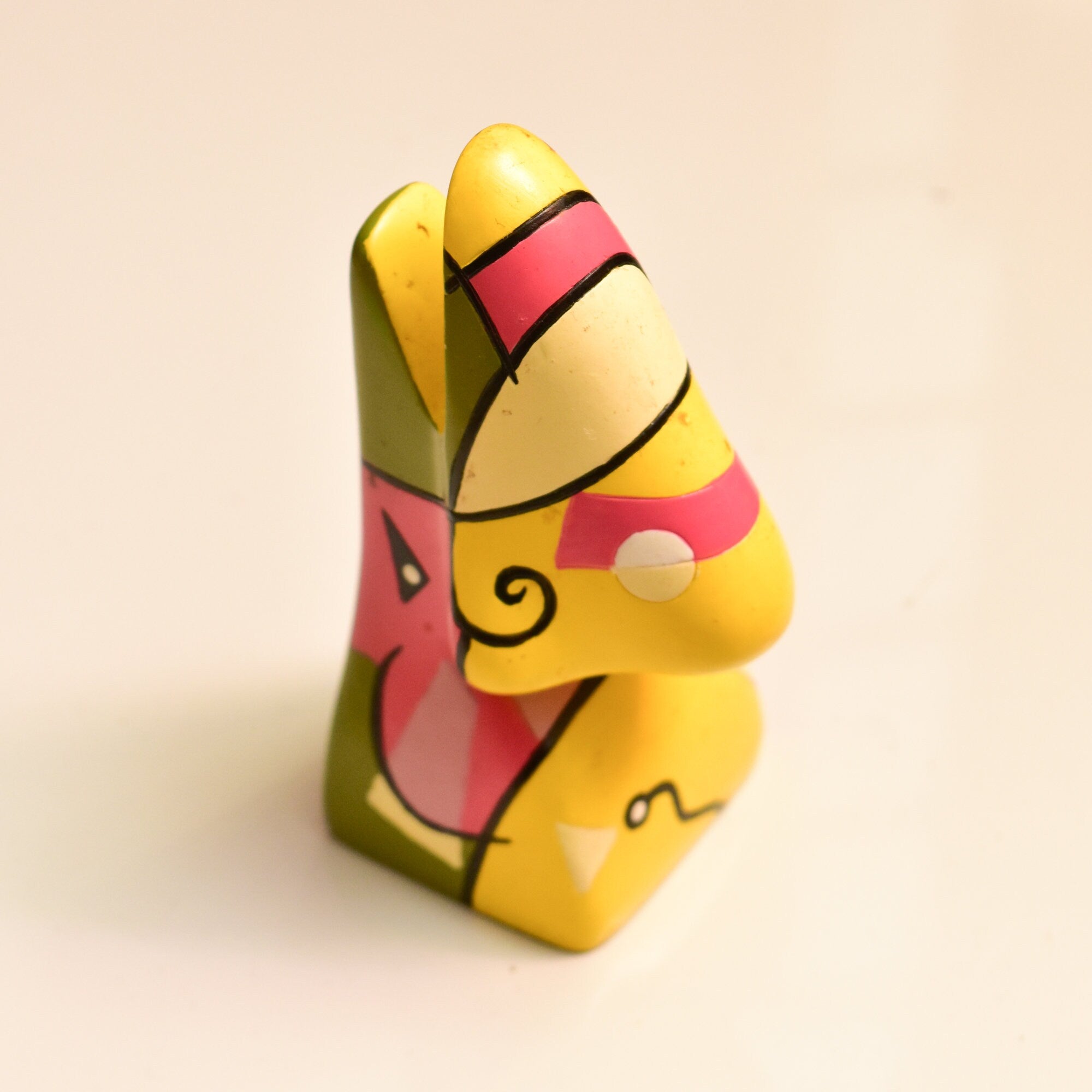 Colorful abstract resin eyeglass holder stand shaped like Picasso face with yellow, red and black features, measuring 3 3/4 inches tall, vintage home decor accessory