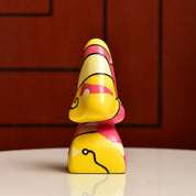 Colorful abstract resin eyeglass stand shaped like a face with distinct geometric features in yellow, pink and black against a red background, measuring 3 3/4 inches tall, vintage home decor accessory.
