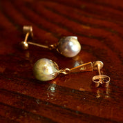18K yellow gold baroque freshwater pearl dangle earrings with pushback closures on wooden surface