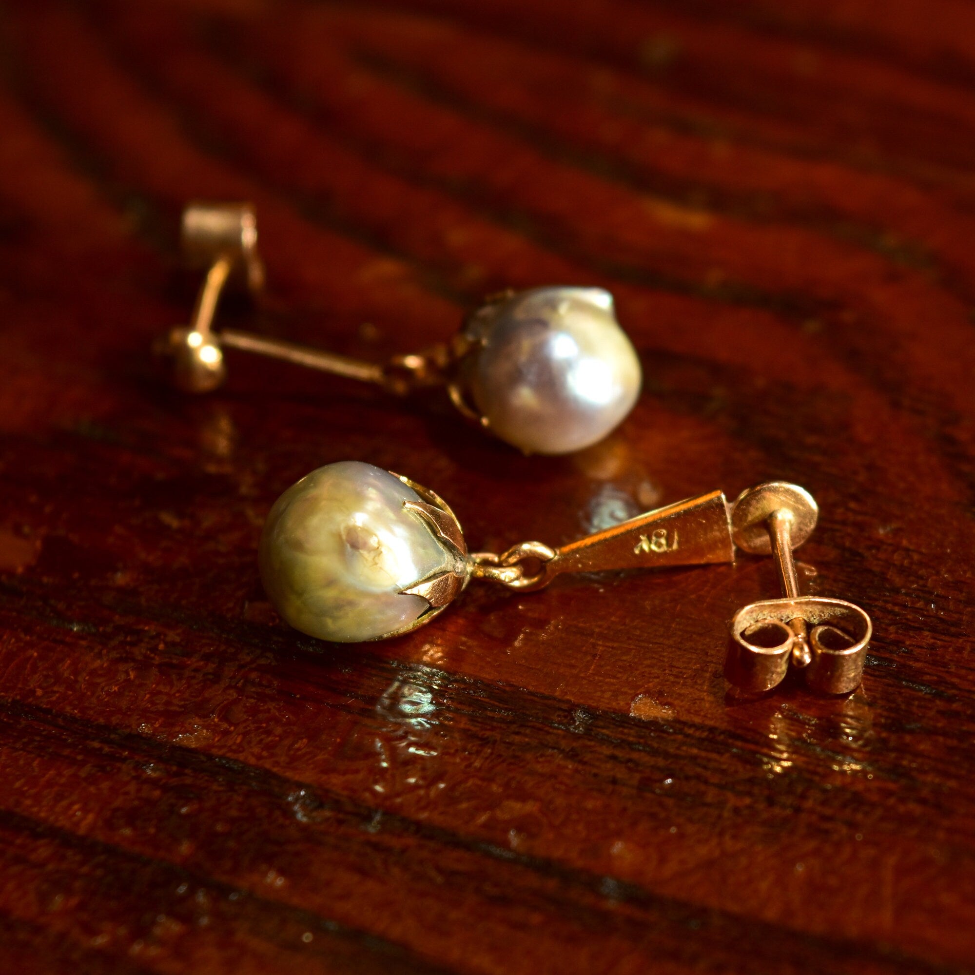 18K yellow gold baroque freshwater pearl dangle earrings with pushback closures on wooden surface