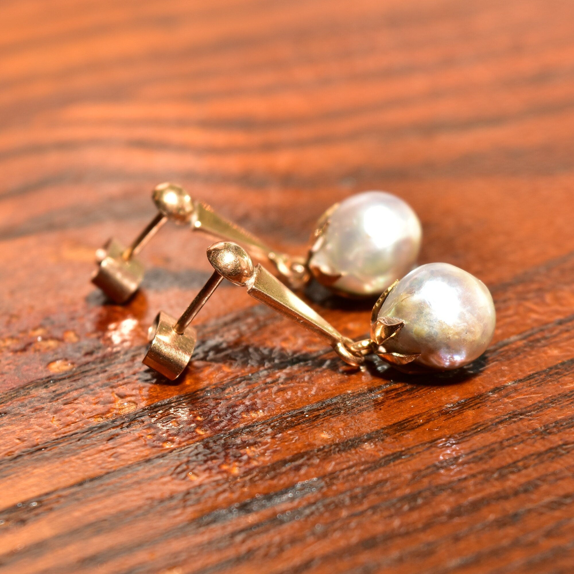 18K yellow gold baroque freshwater pearl dangle earrings with original pushbacks on wooden surface, estate jewelry