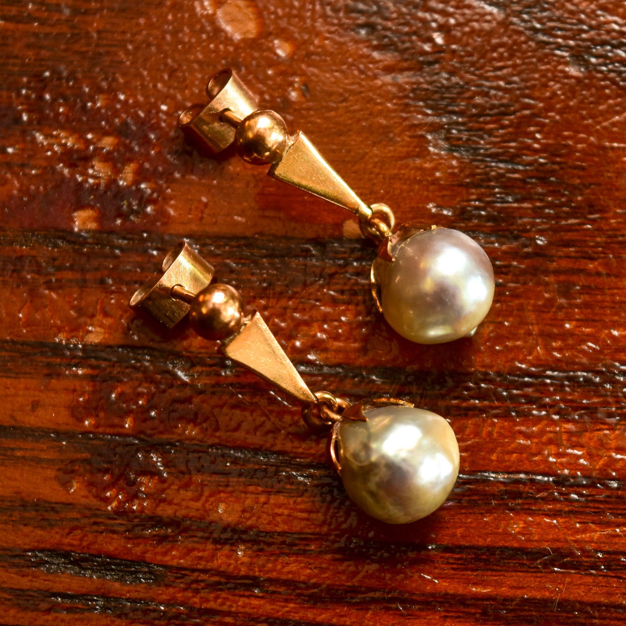 18K yellow gold baroque freshwater pearl dangle earrings with original pushbacks on wooden surface, estate jewelry