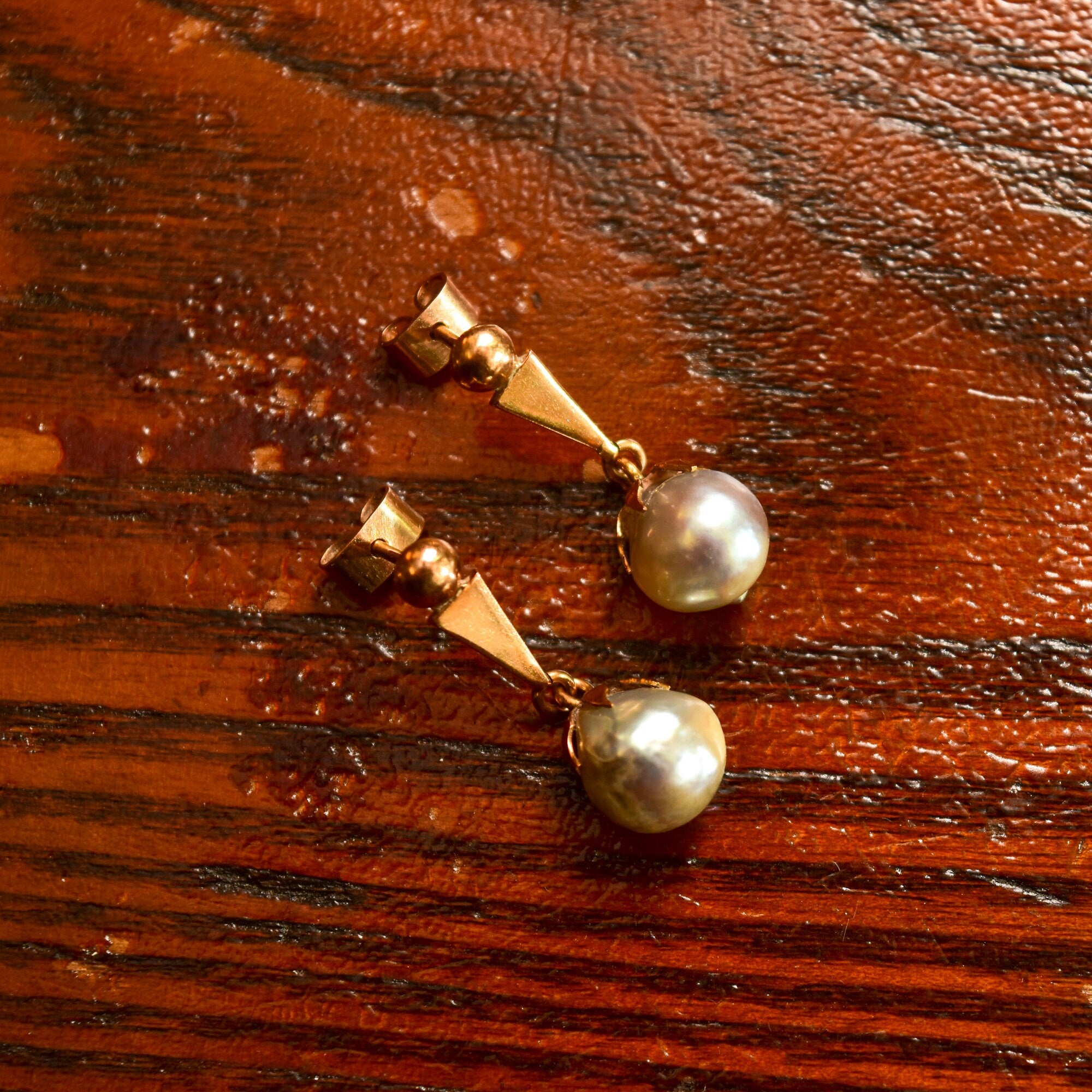 18K yellow gold baroque freshwater pearl dangle earrings with original pushbacks on wooden surface, estate jewelry, 29mm in length