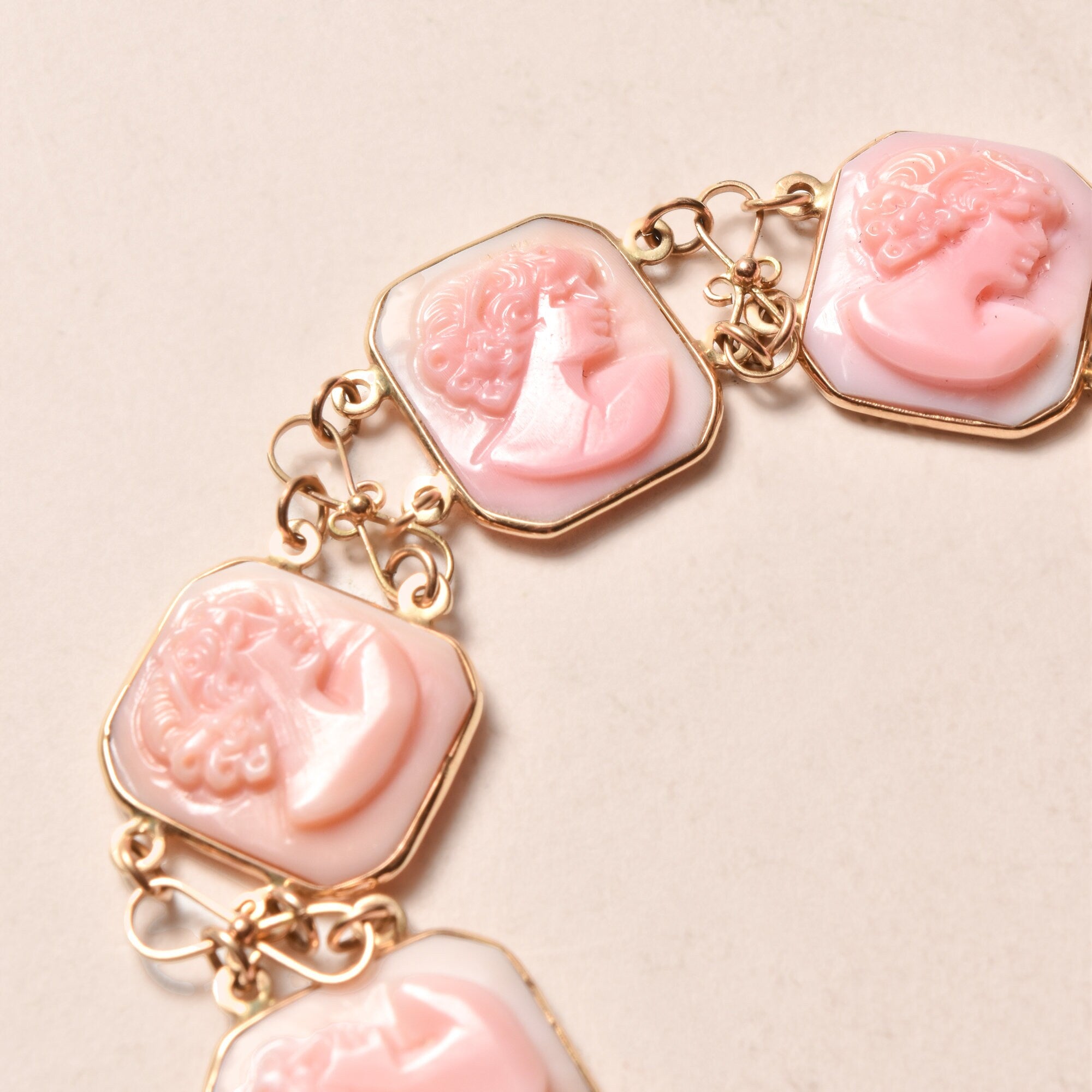 Antique pink carved shell cameo bracelet with 14K gold setting, featuring 6 cameo links depicting classical female profiles, signed by Italian maker M+M SCOGNAMIGLIO. The delicate bracelet measures 7 1/4 inches long and is an elegant estate jewelry piece showcasing fine Italian craftsmanship.
