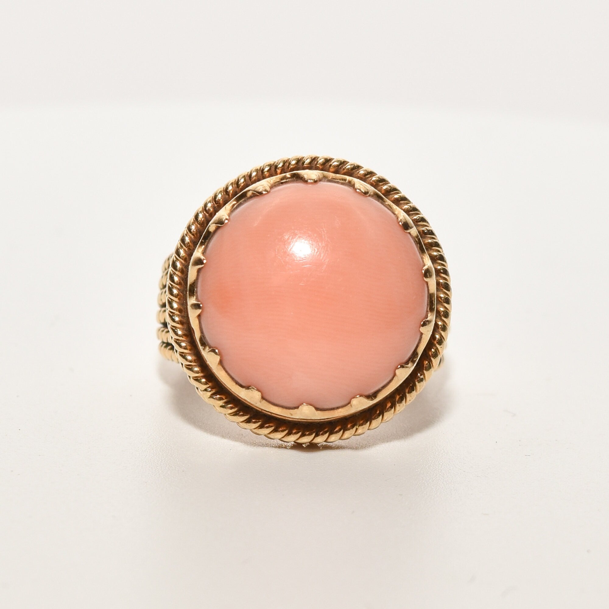 Estate angel skin coral cocktail ring in 18K yellow gold with a woven band, size 6.25 US, displayed on a white background.