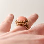 Elegant estate angel skin coral cocktail ring in 18K yellow gold with a woven gold band, size 6.25, showcased on a finger with a close-up view.